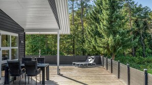 Eine Terrasse mit Gartenmöbeln, einer Pergola und Blick auf einen bewaldeten Bereich.