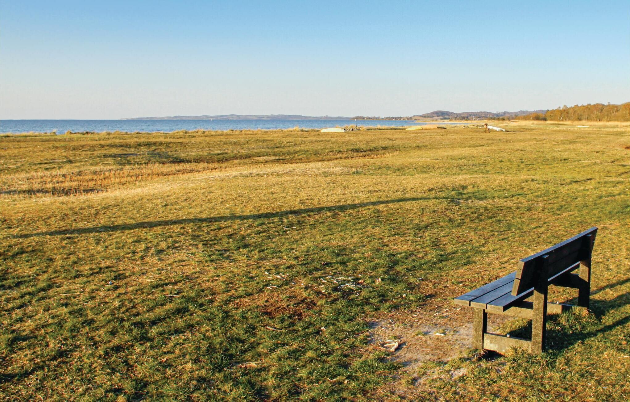 Un banc dans un champ verdoyant, offrant une vue sur la mer et les collines lointaines.