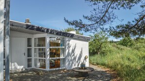 A modern house with large glass windows, a concrete patio, and a small garden area.