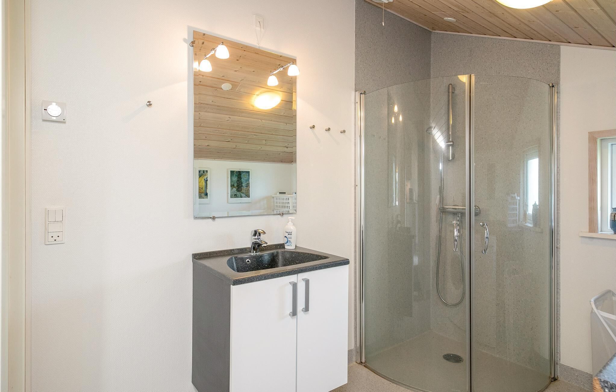 Une salle de bain avec une douche à parois de verre, un lavabo avec un plan de travail et un miroir au-dessus du lavabo.