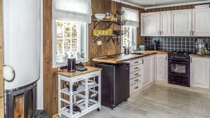 A kitchen with wooden cabinets, a black stove, a sink, and a white refrigerator.