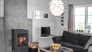 A living room with a fireplace, a sofa, a television, and a window with curtains.