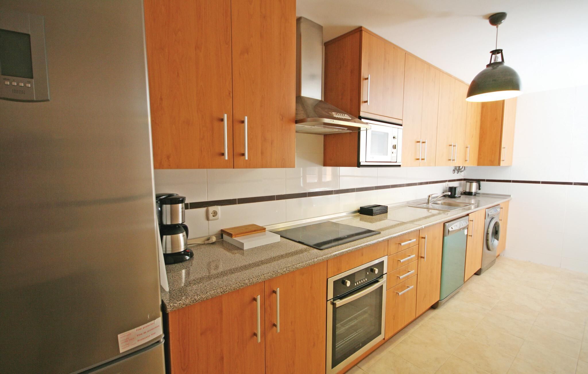 A modern kitchen with wooden cabinets, stainless steel appliances, a built-in oven, and a microwave.