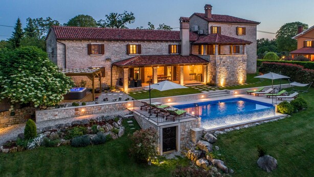 A stone house with a swimming pool, outdoor seating, and a hot tub.