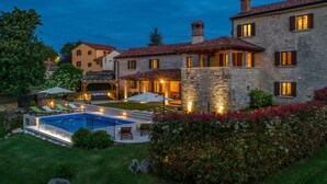 A large stone house with a swimming pool, outdoor seating, and a well-maintained garden.