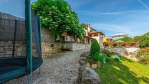 A stone pathway leading to a house with a covered patio area.