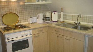 A compact kitchen with a stove, oven, sink, and basic appliances. - 2 - - - floor 3 room (BC. A3) - BARLT - Ferienhaus Bärbel (Barlt)