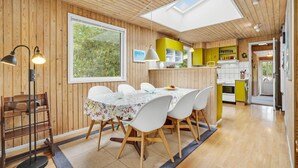 A dining area with a table set for four, a wooden ceiling, and a view of the outdoors through a large window. - Pet friendly home in Hadsund with sauna (Hadsund)