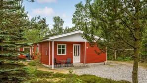 A red cabin with a white door and windows, surrounded by trees and a gravel path. - Pet friendly home in Hadsund with sauna (Hadsund)