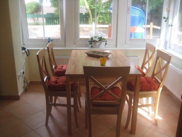 Un comedor con una mesa y sillas de madera, una ventana con vistas al exterior, y un florero sobre la mesa.
