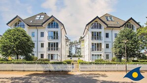 A modern two-story residential building with a symmetrical facade, large windows, and a white picket fence in front. - Villa Strandperle, Whg. 33 // - VS 33 (Heringsdorf)