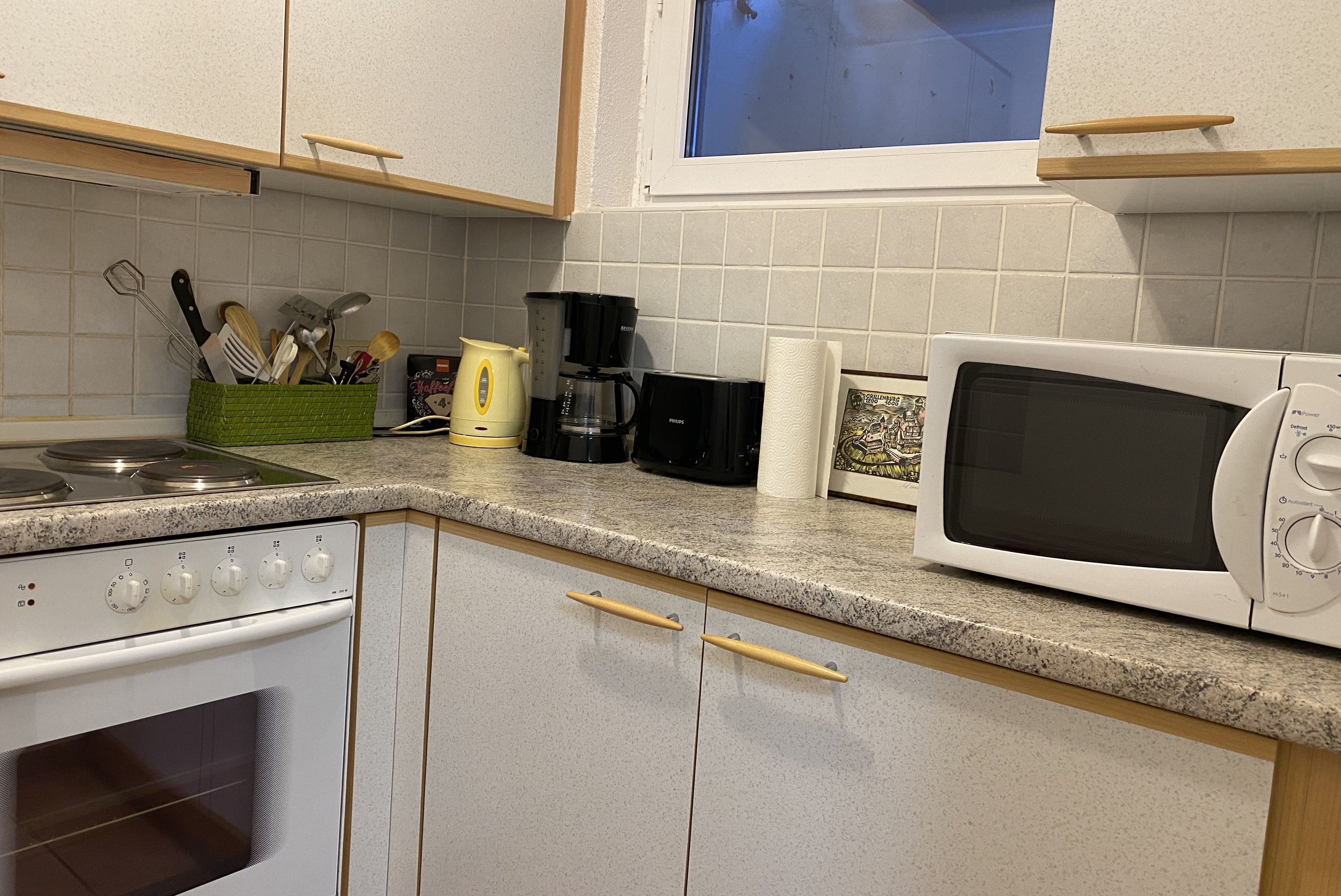 Una cucina accessoriata con fornello, forno a microonde, macchina del caffè e utensili.