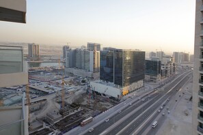 A high-rise building with a modern glass facade, surrounded by other high-rise buildings and a busy highway. - Piks Key - Burj Views B (Dubai)