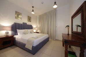 A neatly arranged bedroom with a large bed, two bedside tables with lamps, a wooden dresser, and a mirror. - Piks Key - Burj Views B (Dubai)