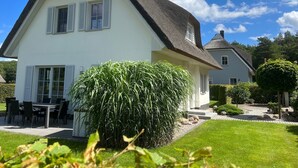 A two-story house with a steeply pitched roof, white exterior walls, and shutters. - Holiday home Strandmuschel - FH Strandmuschel (Loddin)