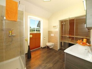 A modern bathroom with a glass shower enclosure, a white sink, and a toilet.