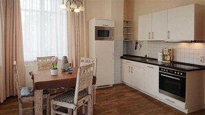 Een keuken met een eettafel, stoelen, een magnetron, oven en kasten.