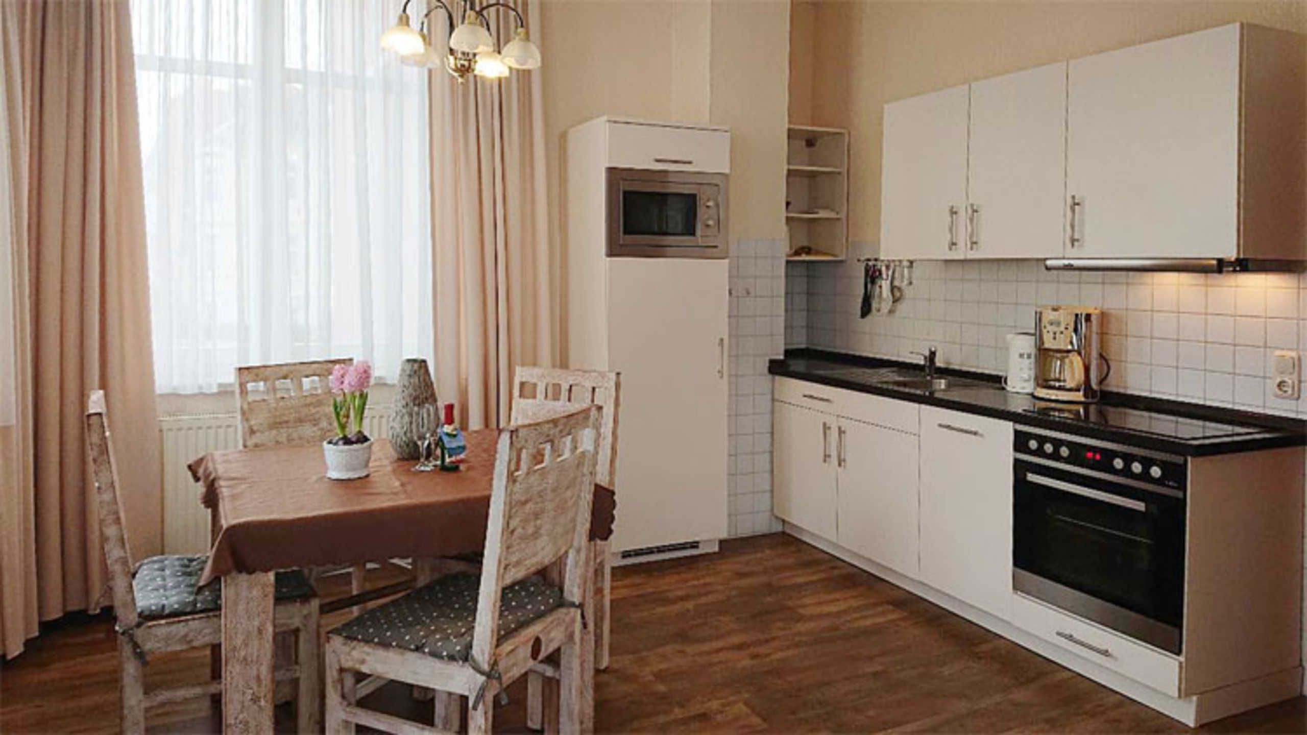 A kitchen with a dining table, chairs, a microwave, oven, and cabinets.