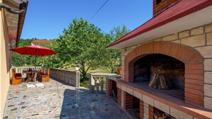 An outdoor patio with a brick oven, stone flooring, and wooden furniture. - Cozy apartment in Viskovo with WiFi (Viskovo)