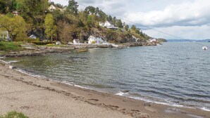 A coastal area with a sandy beach, a rocky shoreline, and houses on a hillside. - 3 bedroom awesome home in Nordre Frogn (Nordre Frogn)