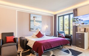 Habitación de hotel con cama, televisor, escritorio y ventana grande.