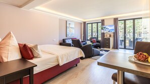 A hotel room with a bed, a desk, a chair, a TV, and a view of the outdoors. - Beach front apartment in Binz with indoor swimming pool (Prora/Rügen)