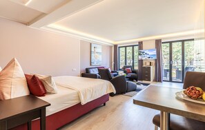 A hotel room with a bed, a desk, a chair, a TV, and a view of the outdoors. - Beach front apartment in Binz with indoor swimming pool (Prora/Rügen)