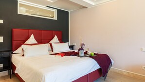 Ein modernes Schlafzimmer mit einem roten, gepolsterten Kopfteil, einem großen Spiegel und einem Nachttisch mit einer Lampe.