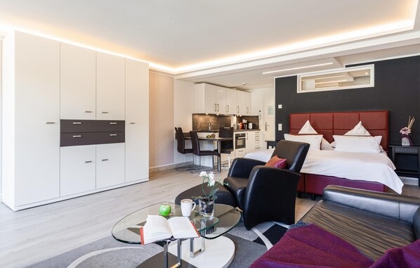 A modern hotel room with a bed, a seating area, and a kitchenette. - Beach front apartment in Binz with indoor swimming pool (Prora/Rügen)
