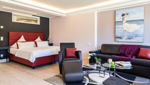 A modern hotel room with a bed, a sofa, a chair, a coffee table, and a painting on the wall. - Beach front apartment in Binz with indoor swimming pool (Prora/Rügen)