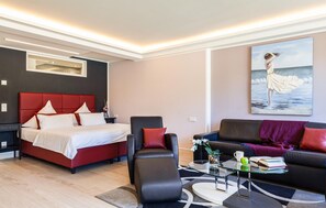 A modern hotel room with a bed, a sofa, a chair, a coffee table, and a painting on the wall. - Beach front apartment in Binz with indoor swimming pool (Prora/Rügen)