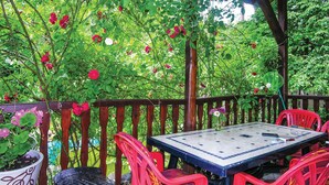 Een terras met een tafel en stoelen, omringd door een houten omheining en weelderige beplanting.