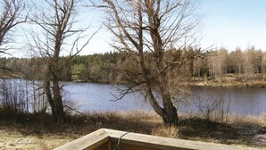 A wooden deck overlooking a calm lake with trees in the background. - 4 bedroom nice home in Bottnaryd (Bottnaryd)
