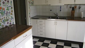 A kitchen with white cabinets, a black and white checkered floor, and a wooden countertop. - 4 bedroom nice home in Bottnaryd (Bottnaryd)