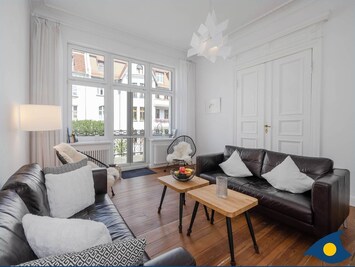 Wohnbereich mit Couch, TV und Blick zum Balkon