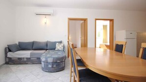 Un espacio habitable compacto con sofá, reposapiés, mesa de comedor, sillas y kitchenette.