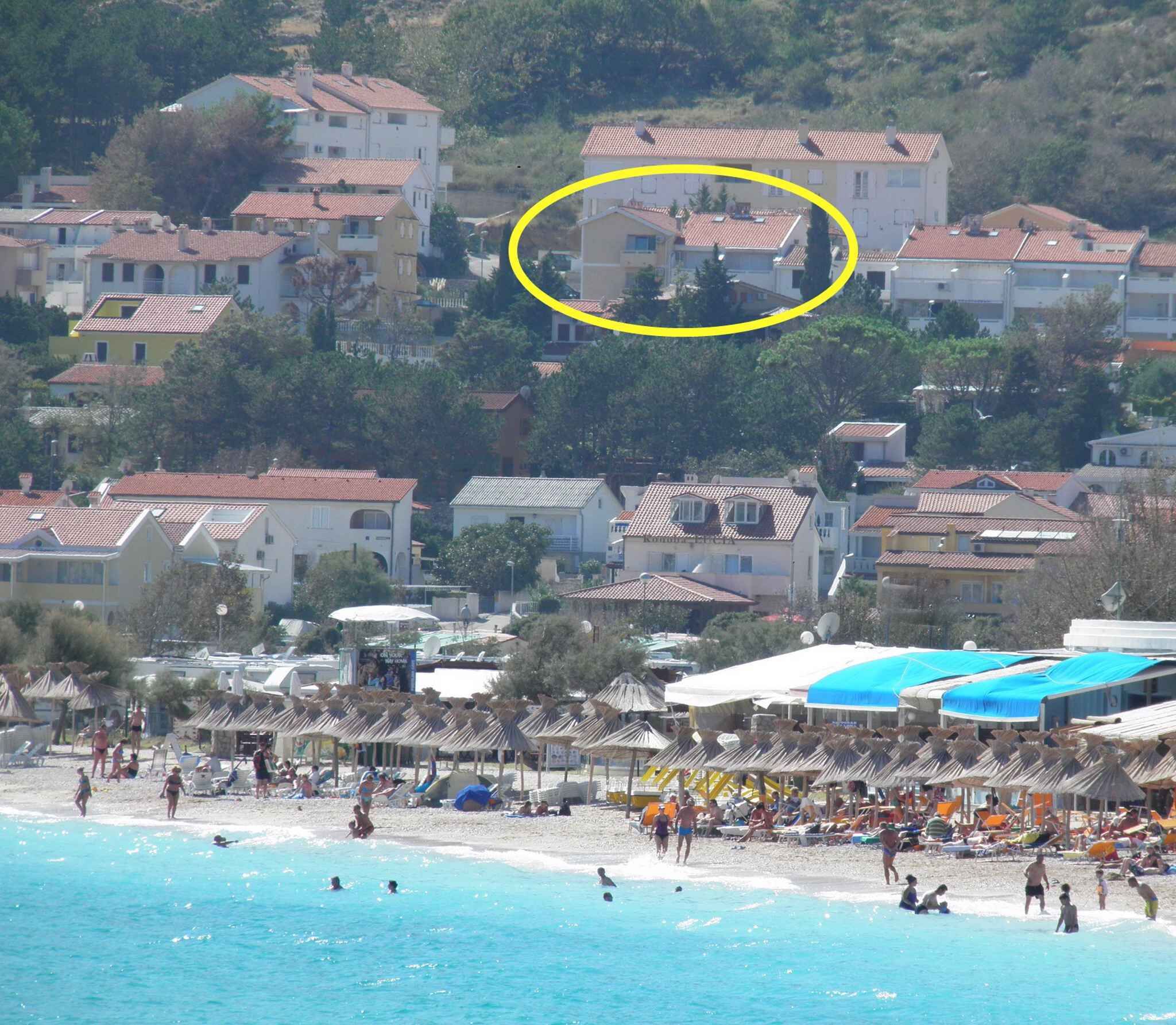 Un poble costaner amb una platja, sombrerets de platja i gent gaudint del mar.