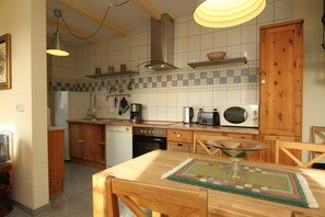 Eine Küche mit Holzausstattung, einem Geschirrspüler, einem Herd, einer Mikrowelle und einem Esstisch mit Stühlen.