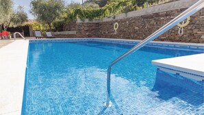 A clear blue pool with a stone wall and a metal ladder. - Beautiful home in Sayalonga (Sayalonga)