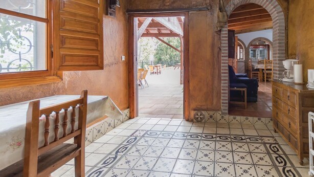 A rustic interior with a wooden bench, tiled floor, and a view of an outdoor patio area. - Beautiful home in Sayalonga (Sayalonga)