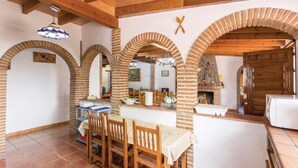 A rustic dining area with brick arches, wooden furniture, and a brick fireplace. - Beautiful home in Sayalonga (Sayalonga)