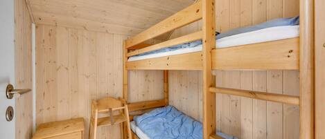 Una camera con un letto a castello, una scala in legno e un piccolo comò di legno.