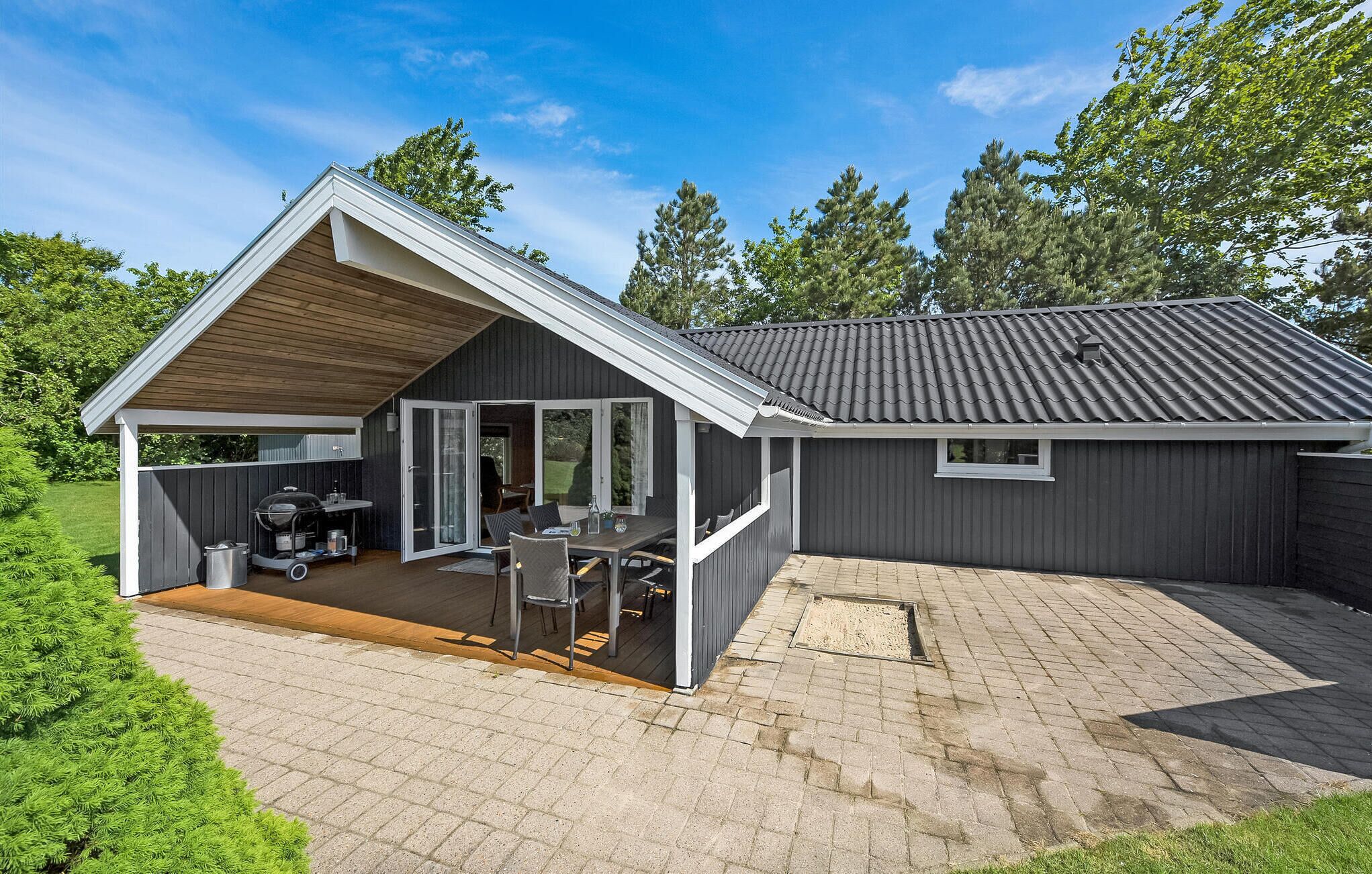 A modern house with a covered patio, a garage, and a well-maintained lawn.
