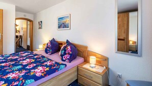 Quarto de hotel com uma cama, mesas de cabeceira, um espelho e uma porta que dá para outro cômodo.
