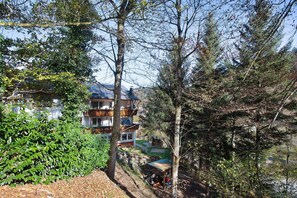 Ein mehrstöckiges Gebäude mit Balkon, umgeben von dichter Vegetation und blauem Himmel.