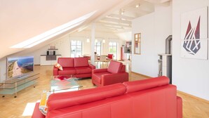 Amplia sala de estar con un sofá rojo, una mesa de centro de vidrio y un televisor de pantalla plana.