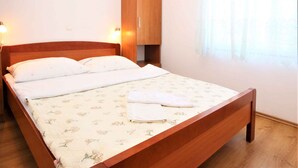 Une chambre à coucher avec un lit en bois, deux lampes de chevet, une armoire et une fenêtre avec des rideaux.