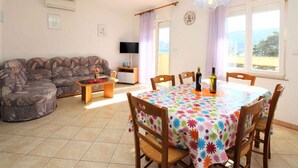 Un salon comprenant un canapé, une table basse, un téléviseur et une table à manger avec des chaises.