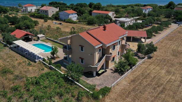 Zona residencial con casas, piscina y vista al mar.
