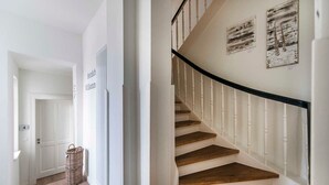Una escalera de madera con barandas blancas que conduce a una plataforma con una puerta marcada con el número 4.
